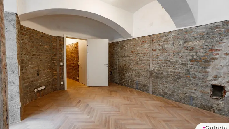 Geräumiger Innenraum mit freigelegten Ziegelwänden, Fischgrätparkett und charakteristischen Gewölbedecken.