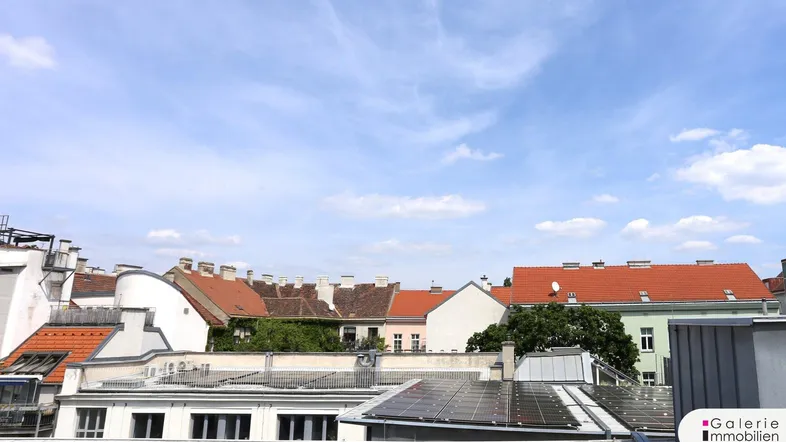 Panoramablick über die Dächer der Stadt mit traditionellen Ziegeldächern und Solaranlagen.