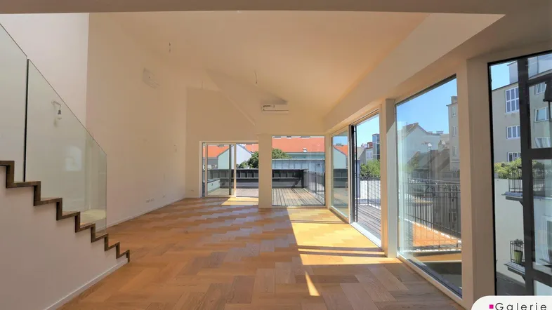 Helles, geräumiges Wohnzimmer mit Fischgrätparkett, großen Fensterfronten und Zugang zur Dachterrasse.
