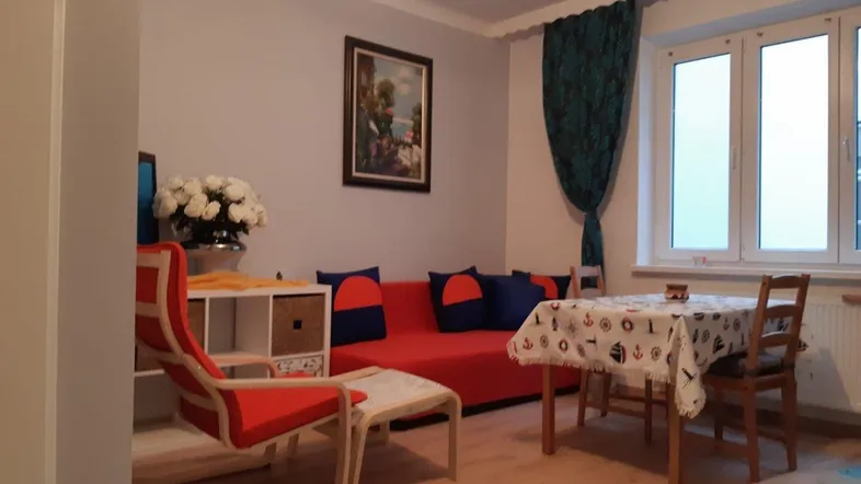Gemütlicher Wohn-Essbereich mit rotem Sofa, Esstisch und hellem Fenster.