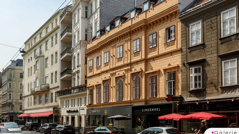 Historisches Gebäude mit klassischer Fassade und Geschäften an einer belebten Straße.