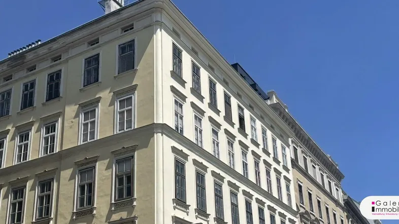 Klassische Altbaufassade mit vielen Fenstern und eleganten Details unter einem klaren blauen Himmel.