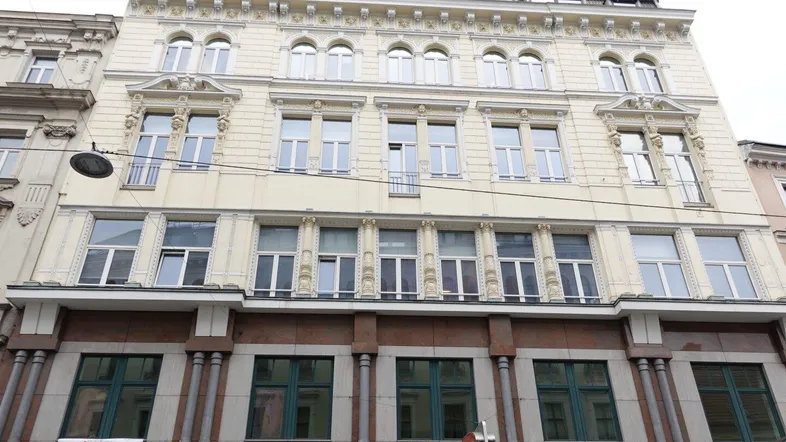 Klassische Fassade eines Mehrfamilienhauses mit vielen Fenstern und dekorativen Elementen.