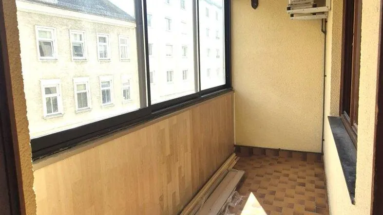 Verglaste Loggia mit Fliesenboden und Blick auf die umliegenden Gebäude.