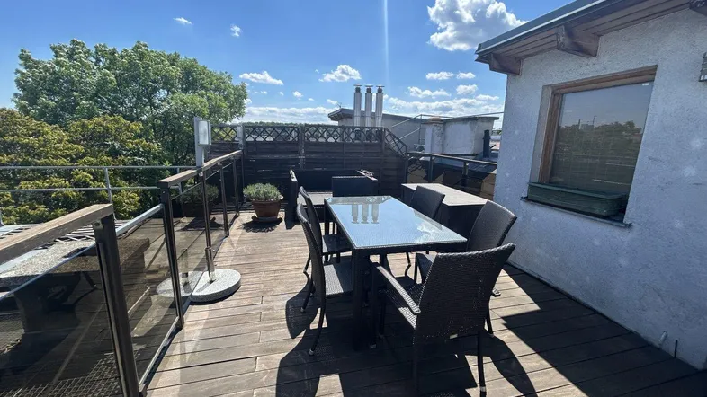 Geräumige Dachterrasse mit Holzboden und bequemen Gartenmöbeln, ideal für entspannte Stunden im Freien.