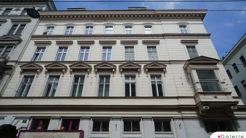 Historische Gebäudefassade mit vielen Fenstern und dekorativen Elementen, die den Charme des Altbaus unterstreichen.