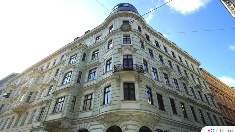 Historisches Eckgebäude mit eleganter Fassade und klassischen Fenstern unter blauem Himmel.