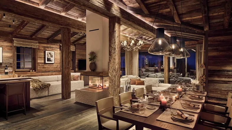Gemütlicher Wohn- und Essbereich im Chalet-Stil mit Holzbalken und modernem Kamin.