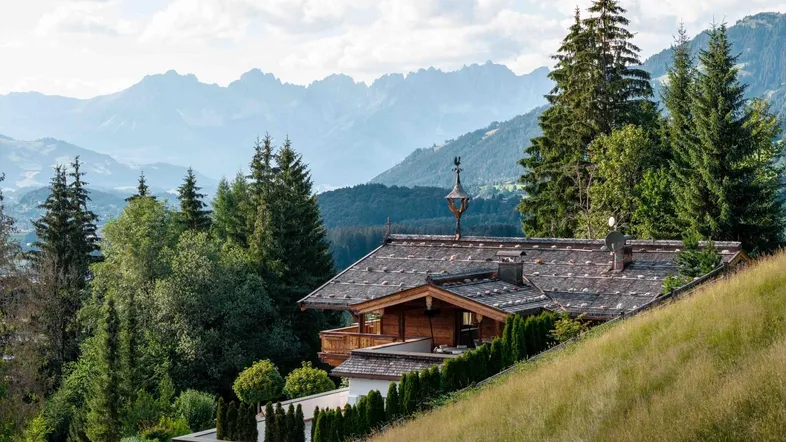 Charmantes Chalet im alpinen Stil auf einem Hügel mit Bergblick und grüner Umgebung.