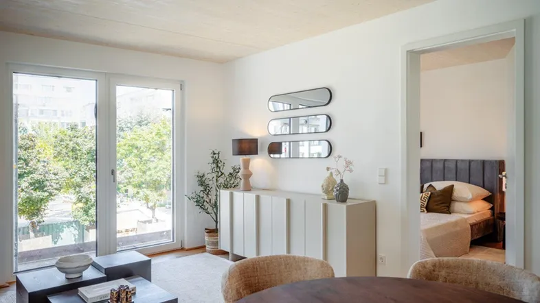 Heller Wohnbereich mit großen Fenstern, Blick ins Grüne und modernem Interieur.