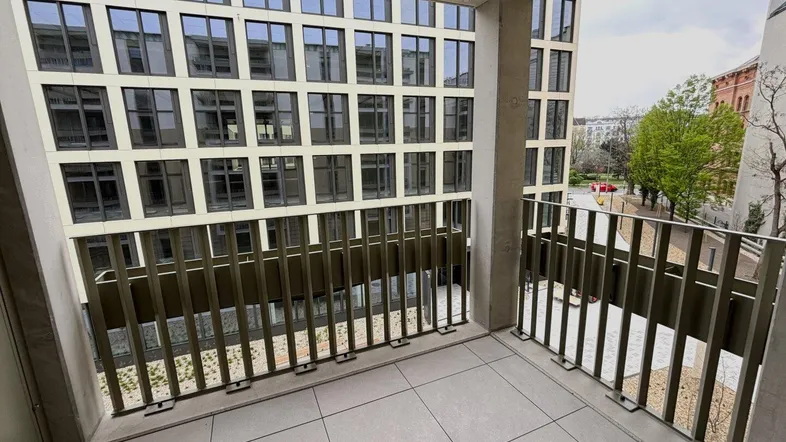 Moderner Balkon mit Fliesenboden und Blick auf die gegenüberliegende Gebäudefassade in der Stadt.