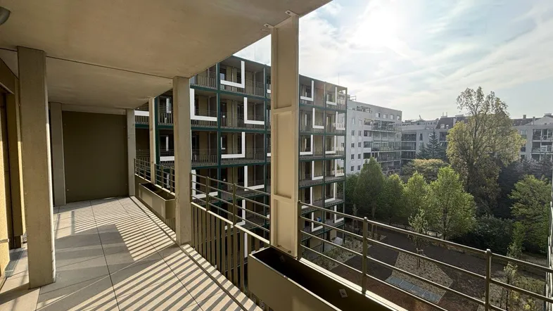 Geräumiger Balkon mit Fliesenboden und Blick auf den Innenhof und umliegende Gebäude.
