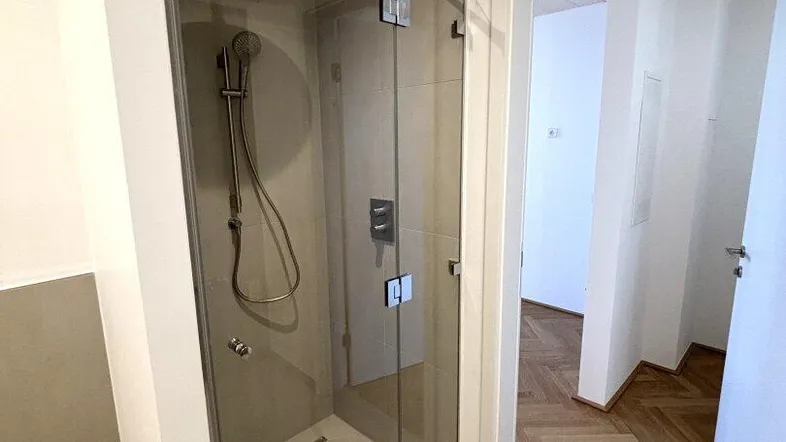 Modernes Badezimmer mit begehbarer Dusche, Glasabtrennung und eleganten Fliesen.