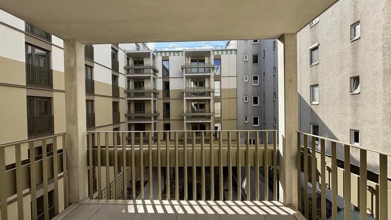 Balkon mit Blick auf den Innenhof und die umliegenden Gebäudefassaden des Neubaus.