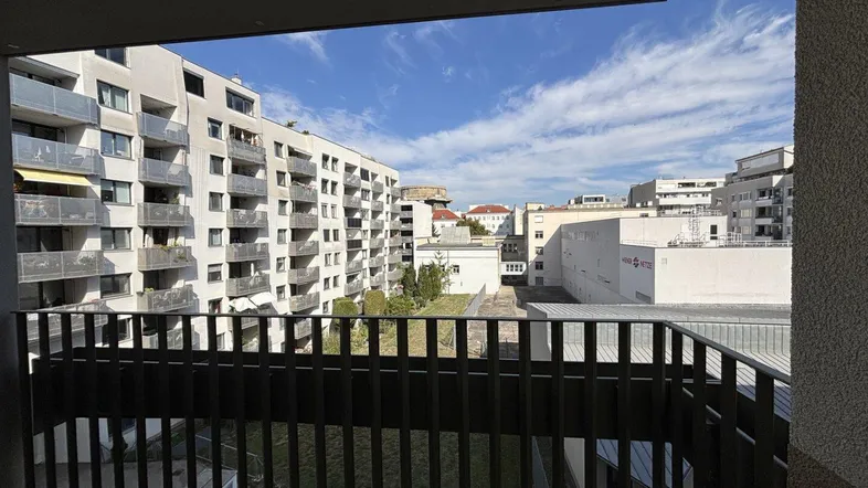 Blick vom Balkon auf die umliegenden Wohngebäude und den begrünten Innenhof.