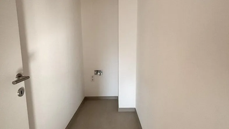 Funktionaler Hauswirtschaftsraum mit Fliesenboden und Anschlüssen für zukünftige Geräte.