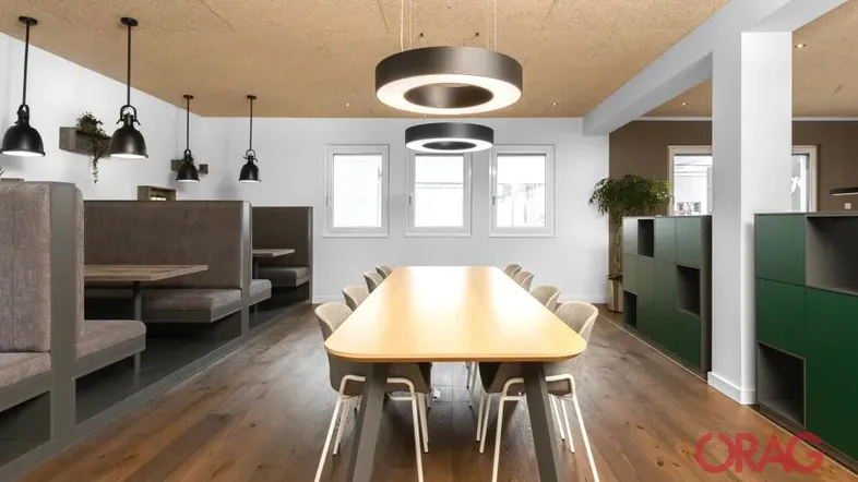 Moderner Konferenzraum mit Holzboden, Akustikdecke und bequemen Sitzgelegenheiten für Besprechungen.