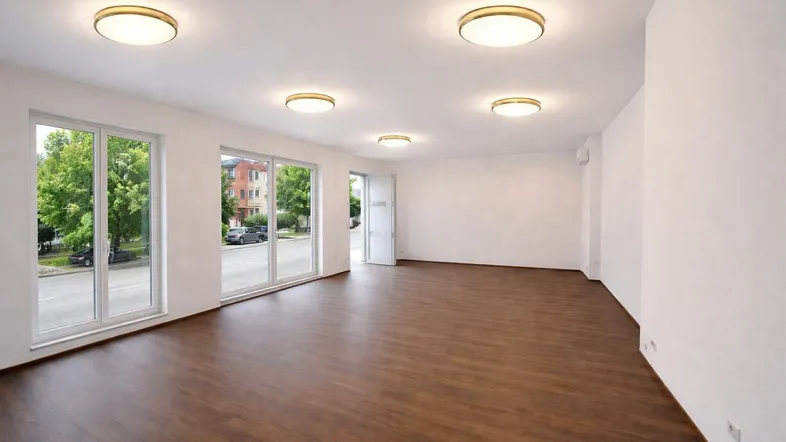 Großer, heller Raum mit großen Fenstern und Blick auf die Straße, ausgestattet mit modernem Laminatboden und Deckenleuchten.