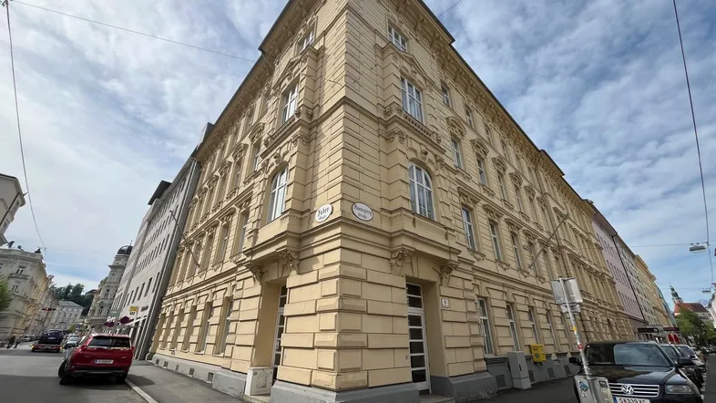Historisches Eckgebäude mit klassischer Architektur und vielen Fenstern an einer städtischen Straße.