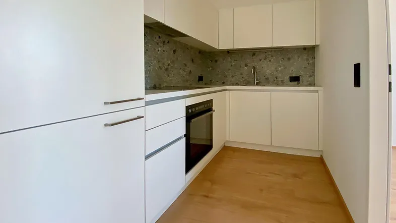 Moderne Einbauküche in Weiß mit integriertem Backofen und Laminatboden, in neuwertigem Zustand.