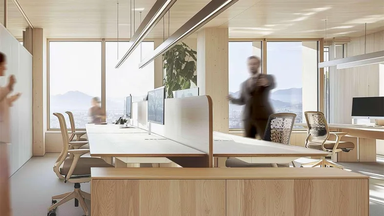Modernes Großraumbüro mit Holzelementen, großen Fenstern und ergonomischen Arbeitsplätzen sowie Bergblick.