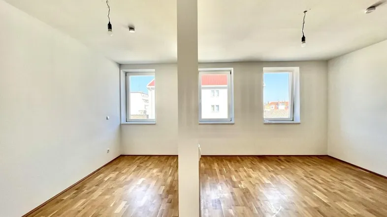 Helles, leeres Zimmer mit Parkettboden und mehreren Fenstern, bereit zur individuellen Gestaltung.