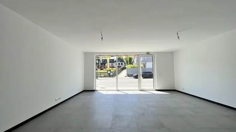 Heller, leerer Raum mit großen Glasfronten und Blick auf die Straße, ideal für Gewerbe.