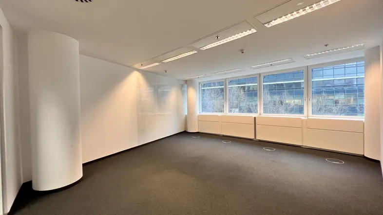 Geräumiges Büro mit Teppichboden, großen Fenstern und integrierter Deckenbeleuchtung sowie Belüftungssystem.