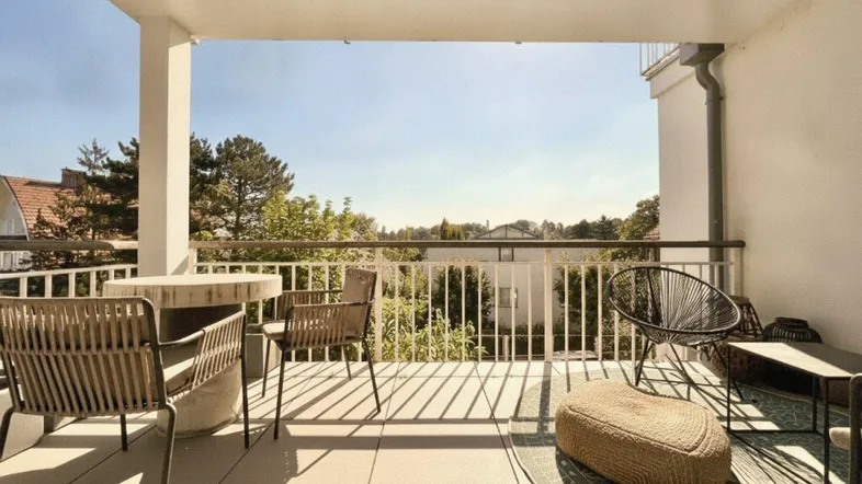 Geräumiger Balkon mit modernen Outdoor-Möbeln und weitem Blick ins Grüne.