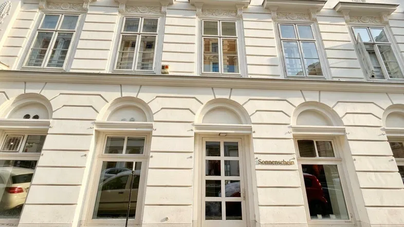 Historische Fassade eines Gebäudes mit großen Fenstern und einem Eingangsbereich im Erdgeschoss.