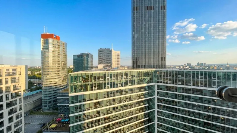 Panoramablick aus einem Hochhaus auf die moderne Stadtlandschaft mit weiteren Wolkenkratzern und klarem Himmel.