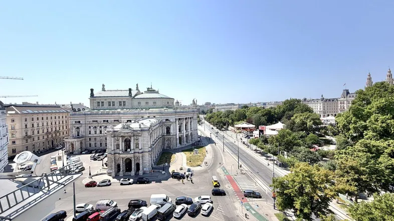 Panoramablick über die Stadt Wien mit historischen Gebäuden und belebten Straßen unter blauem Himmel.