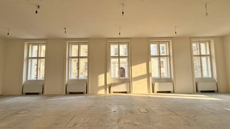 Großer, heller Raum mit mehreren hohen Fenstern und viel Tageslicht, ideal für Büronutzung.