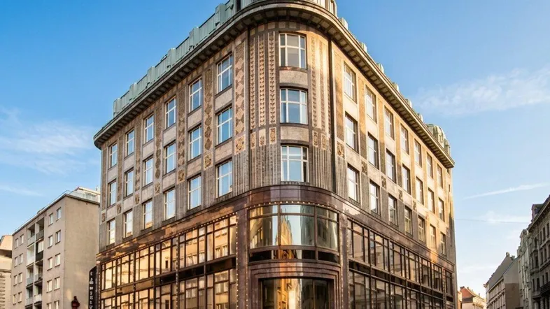 Historisches Eckgebäude mit markanter Fassade und vielen Fenstern in einer belebten Stadtstraße.
