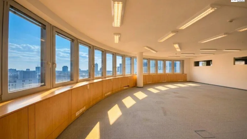 Großer, heller Büroraum mit gebogener Fensterfront, Teppichboden und weitem Stadtblick.
