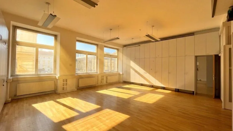 Großes, helles Zimmer mit Holzboden und vielen Fenstern, ideal für Büro oder Gewerbe.