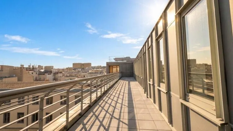 Lange, sonnige Terrasse mit Metallgeländer und Blick über die Stadt, ideal für entspannte Stunden im Freien.