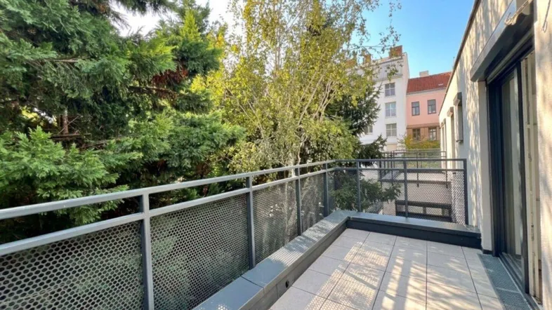 Geräumige Terrasse mit Fliesenboden und Metallgeländer, umgeben von Bäumen und mit Blick auf die Stadt.