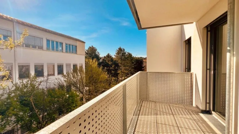 Sonniger Balkon mit moderner Lochblechbrüstung und Blick auf die Umgebung.