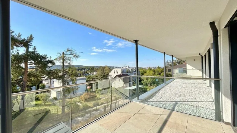 Geräumiger Balkon mit Glasgeländer und weitem Blick über die Umgebung und den Horizont.