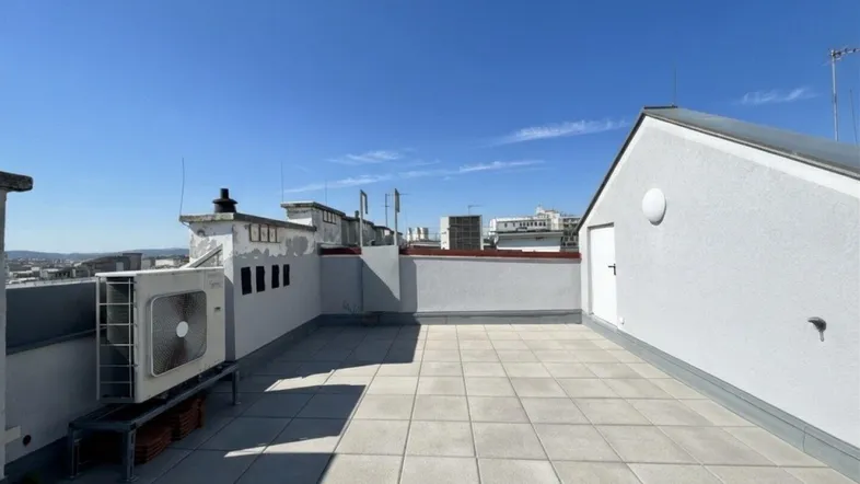Geräumige Dachterrasse mit Fliesenboden und Blick auf die umliegende Stadtlandschaft.