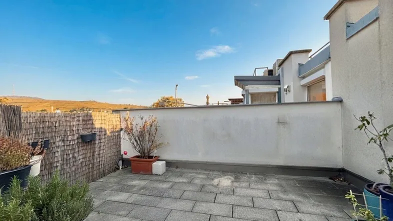 Geräumige Dachterrasse mit Steinplattenboden und Blick auf die umliegende Landschaft.