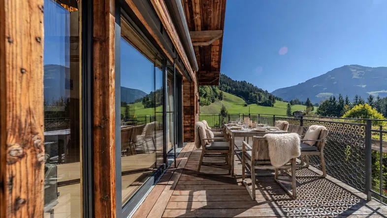 Geräumige Holzterrasse mit Esstisch und Bergblick, ideal für Mahlzeiten im Freien.