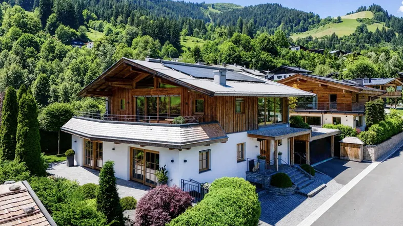 Großzügiges Chalet mit traditioneller Holzfassade und moderner Architektur in alpiner Umgebung.