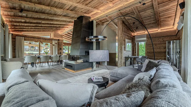 Geräumiger offener Wohn- und Essbereich mit Holzbalkendecke, modernem Kamin und gemütlicher Sitzecke.