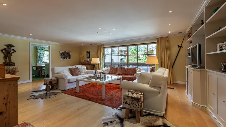 Geräumiges Wohnzimmer mit hellen Sofas, Holzboden und Blick ins Grüne durch große Fenster.