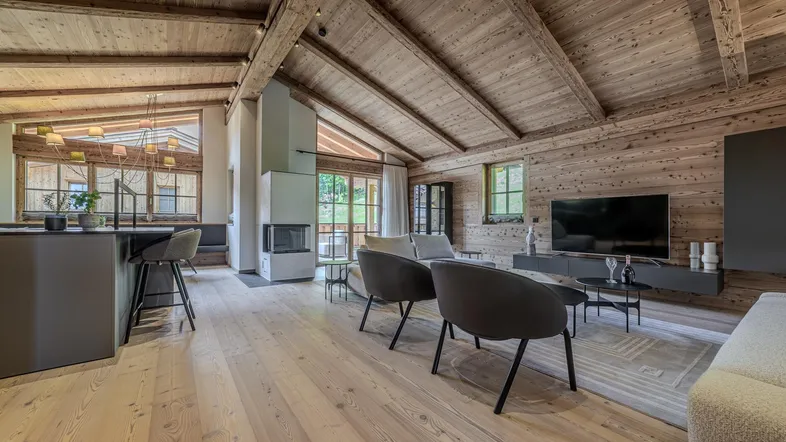Geräumiger Wohn- und Essbereich im alpinen Stil mit Holzbalken, Kamin und moderner Einrichtung.