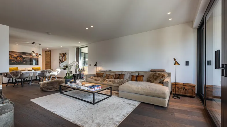 Geräumiger offener Wohn- und Essbereich mit gemütlichem Sofa, Holzboden und Zugang zum Balkon.