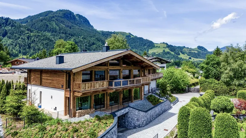 Exklusives Chalet mit Holzfassade und großen Glasflächen, eingebettet in die Berglandschaft.