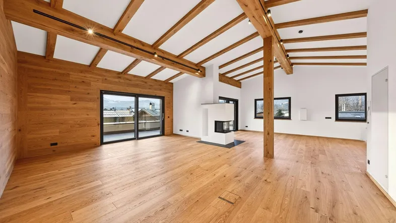Geräumiger Wohnbereich mit Holzbalkendecke, Eichenparkett und modernem Kamin, der viel natürliches Licht erhält.